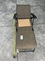 Outdoor lounge recliner chair from top view showing seat and backrest fabric, armrests and black metal frame with leg supports.