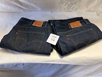 Two folded pairs of Levi's 501 jeans, side by side, showing leather branding patch and denim texture.