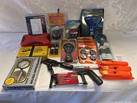 Photo showing all miscellaneous household tools arranged on a white surface, including compression tester, caulking gun, smart dimmer, clip-on work light, Daktron device, stock finish kit, and various hand tools