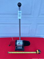 Front view of electric shoe polisher with red and black dual brushes and adjustable handle on red table