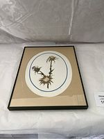 Framed vintage botanical art print with beige matting and black frame showing a thistle plant illustration.