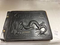 Front cover of the photo album showing black leather with embossed dragon and ship design, gold lettering 'China' and owner's name 'Chas. Krusecky'.