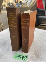 Two volumes of 'Voyages of Champlain' standing upright, showing spines and covers.
