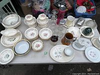 Overview of the entire lot showing various dishes, bowls, plates, tea cups, glassware, and other kitchenware arranged on a table.