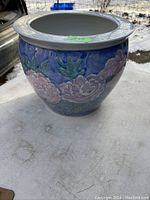 Porcelain Asian flower pot showing the floral design, colors, and texture with a wide rim etched with a geometric pattern.