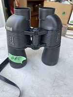 Front view of black Bushnell Perma Focus binoculars showing central focusing knob and textured grip on sides.