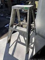 Small aluminum step ladder unfolded showing full height and structural details.