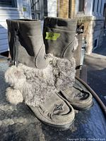 Pair of grey suede winter boots with faux fur trim and beaded star accents visible in natural light.