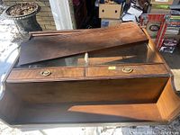 Photo showing the cabinet with the wood cover partially removed revealing the sliding glass doors and two brass-handled drawers beneath.