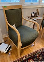 Arm chair angled view showing carved wood frame and dark green cushion upholstery.
