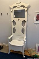 Full view of the white wooden coat tree with seat, mirror, and hooks.