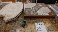 White beaded Simpson's evening bag, tile style trivet, and sterling silver ring arranged on counter.
