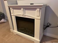 White electric fireplace with faux mantle, showing front and side profile with power cord visible.