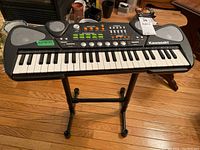 Front view of Kawasaki electronic keyboard on stand showing keys, speakers, and control panel