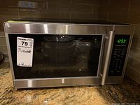 Front view of the stainless steel Hamilton Beach microwave showing digital control panel and display.