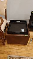 Brown storage ottoman with top flipped into serving tray and placed on top showing front view and tray surface.
