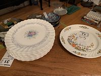 Stack of eight Royal Doulton side plates with central floral pattern and gray leaf border alongside one Aynsley side plate with floral design on rim