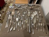 Overview of all cutlery items laid out including forks, spoons, knives, and serving utensils, showing variety of styles and sizes.