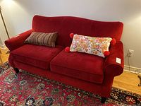 Full front view of red sofa with two decorative cushions