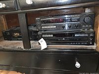 Sony STR AV570 stereo receiver, Sony CDP-C225 CD player stacked, and Sony TC W32 cassette deck visible on a black shelf under a wooden cabinet.