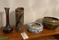 Photo showing all four items: two ceramic vases, one ceramic pot with blue and white floral decoration containing stones, and one decorative brass pot.