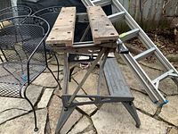 Side view of Black & Decker work bench showing the metal frame, wooden adjustable top with clamping holes, and signs of wear and rust.