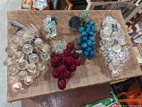 Top-down photo of all 5 antique Bohemian grape bunch clusters on a brown mesh surface showing various sizes and colors.