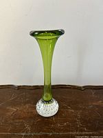 Front view of green glass vase with textured clear bubble base on a wooden surface.