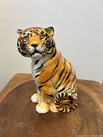 Front view of the ceramic seated tiger sculpture showing detailed painted stripes and facial features.