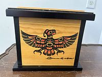 Rectangular cedar box with natural wood finish, black painted edges, and eagle motif signed by Clarence Wells on front.