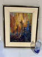 Framed oil painting on board depicting an impressionist forest landscape with fiery autumn colors and bold brushwork. Framed with a wide light beige mat and dark frame with silver trim.