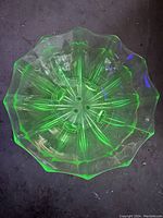 Top-down view of a large fluorescent Vaseline glass berry bowl showing the starburst base pattern and ruffled edge glowing under UV light.