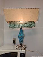 Front view of the mid-century modern lamp showing the powder blue pottery base and double decker parchment shade with abstract pattern.