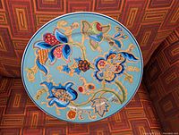 Front view of the decorative wall charger plate showing multicolored floral artwork on blue background.