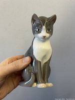 Front view of porcelain cat figurine held in hand showing details and colors.
