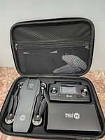 Photo of foldable black Holy Stone drone, its remote controller, and carrying case inside a protective storage case.