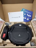 Photo of Lefant robot vacuum cleaner in packaging with charging dock and user manuals.