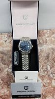 Front view of Pagani Design watch in its branded box showing silver stainless steel construction and blue dial.
