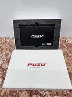 PUZU PZ-C7 digital signal processor device in its original packaging, showing the front face of the unit with branding and model information.