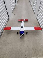 Front view of the RC airplane showing red and white wings, blue nose cone with propeller, and landing wheels.
