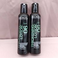 Two black Redken 06 Thickening Lotion bottles, 5 fl oz each, front facing with labels visible.