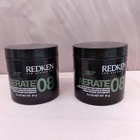 Photo showing two black jars of Redken Aerate 08 volumizing cream-mousse placed side by side on a white background.