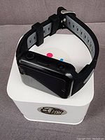 Photo of black W5 4G GPS WiFi smart watch phone with rectangular screen and black/grey silicone strap, placed on white box with a multi-color logo.