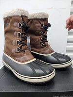 Pair of new Sorel winter boots in size 13, showing brown upper, black waterproof lower, and cream faux fur lining.