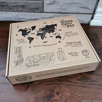 Closed cardboard box with printed world map and travel-themed graphics on top.