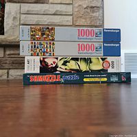 Side view of four stacked puzzle boxes showing titles and pieces count