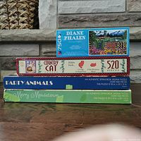 Stacked boxes of the four puzzles showing titles and piece count.