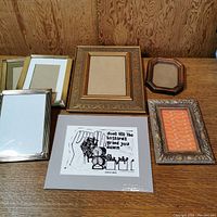 All six frames and the sealed block print art shown laid out on a wooden surface against a wood panel backdrop.