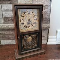 Full view of the Cornwall wooden grandfather mantel clock showing wooden case, glass front, painted dial with Roman numerals, and decorative pendulum