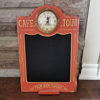 Full view of the French cafe-style red chalkboard sign with integrated round clock at top center showing working time.